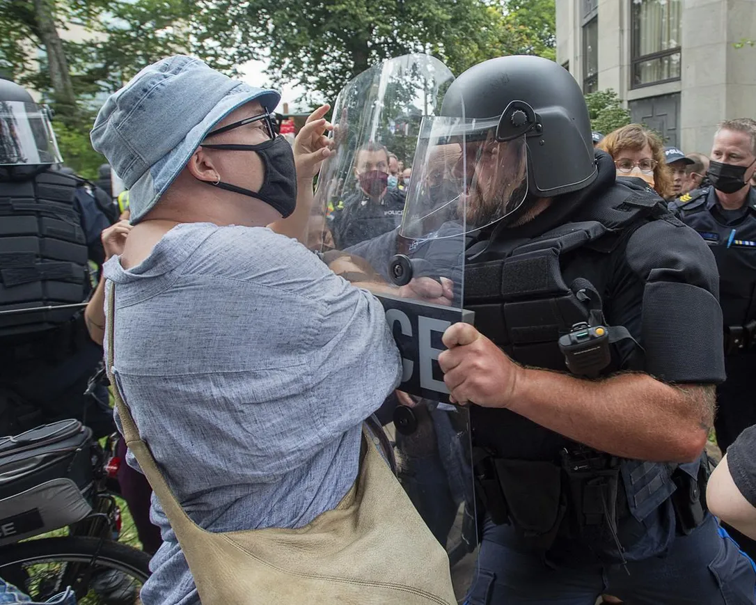 Protesters jostle with police at a protest after the city removed tents and small shelters for homeless people in Halifax on Wednesday, Aug. 18, 2021. A judge has acquitted a man accused of throwing a bottle at police during a Halifax housing protest in one of the first decisions in a series of trials related to the 2021 demonstration.