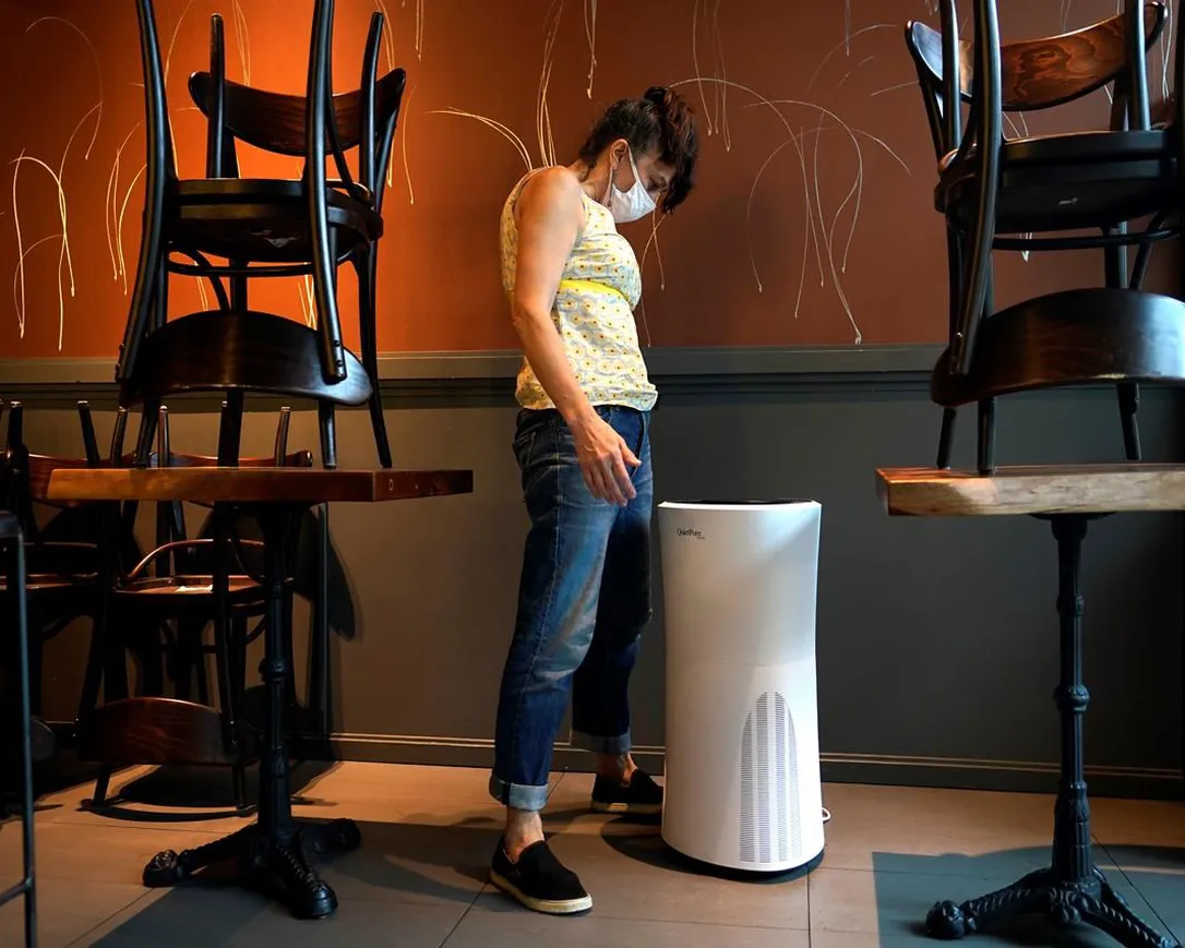Restaurant owner Samantha DiStefano looks over an air purifier in New York, Tuesday, Sept. 29, 2020. The spread of smoke from wildfires across Canada in recent weeks has meant an uptick in demand for air quality products.