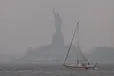 The Statue of Liberty stands shrouded in a reddish haze as a result of Canadian wildfires on Tuesday.