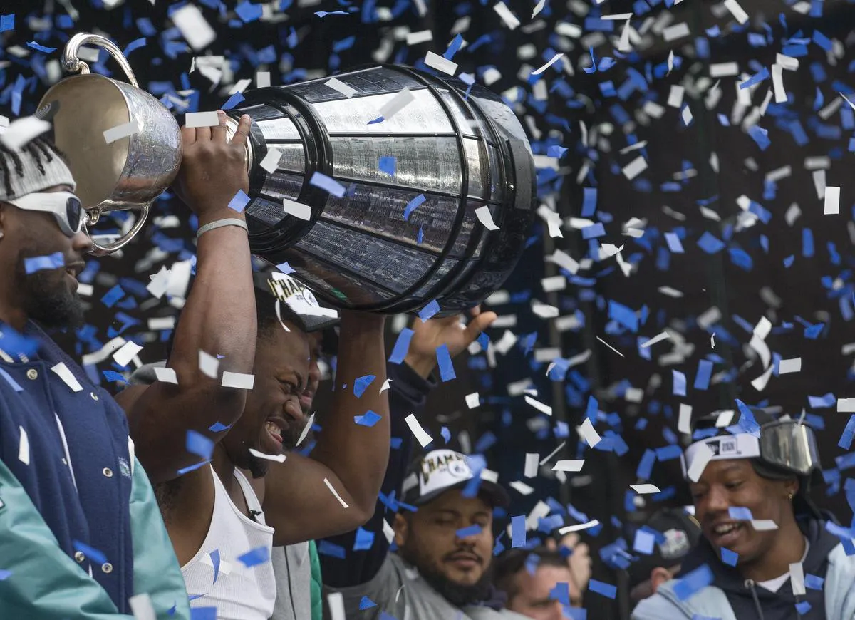 Argos Grey Cup MVP Henoc Muamba hoists the trophy during a rally at Maple Leaf Square.