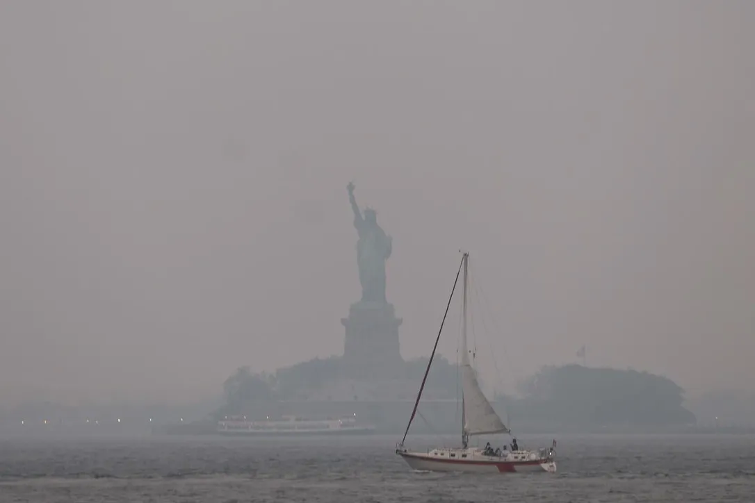 The Statue of Liberty stands shrouded in a reddish haze as a result of Canadian wildfires.